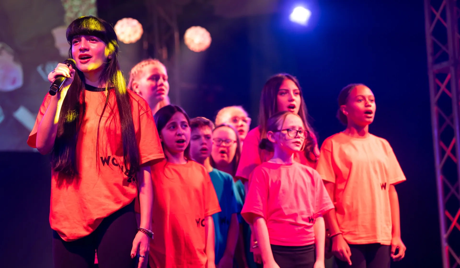 Children perform in bright colours on stage at the Wonder Gala - holding mics and singing