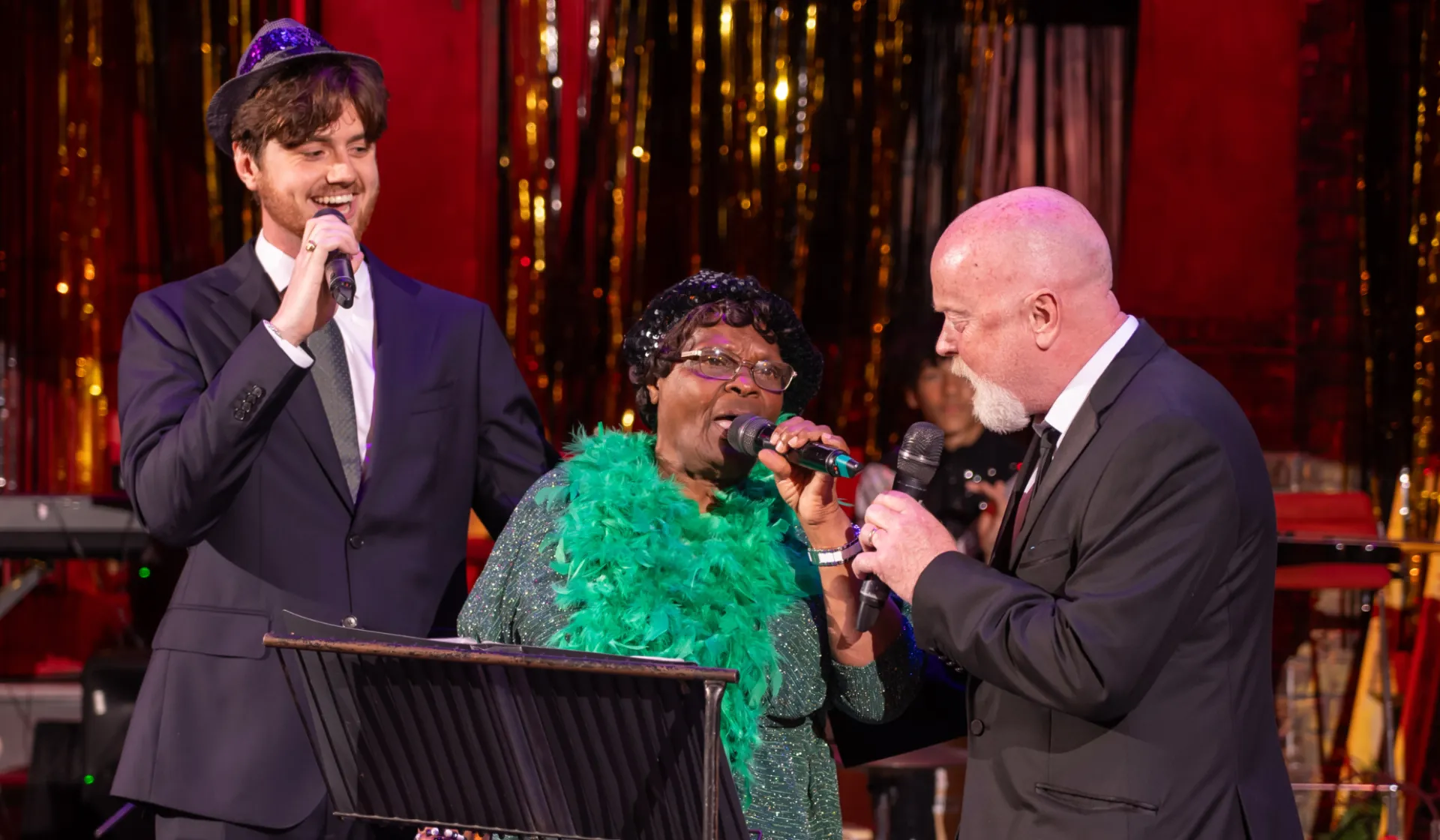 Two men either side of a older lady singing