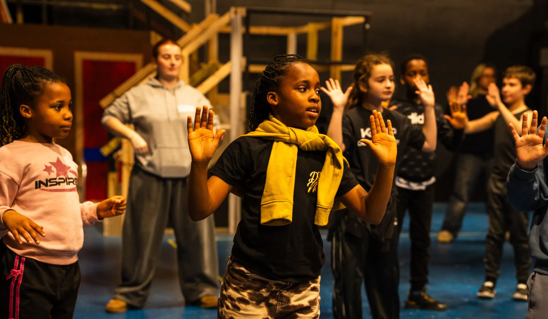 A group of children dancing and acting on stage.