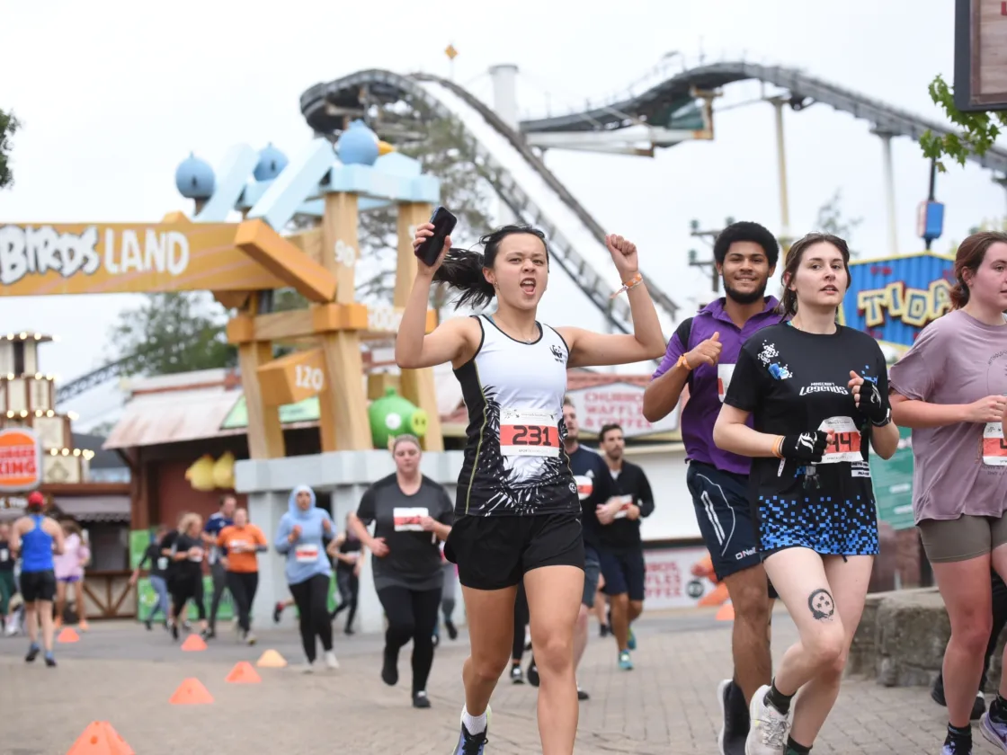 Runners with a rollercoaster behind them at Thorpe park