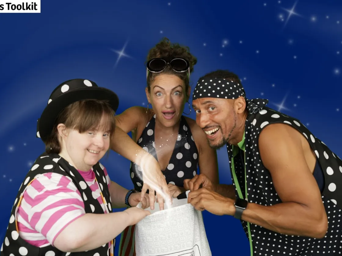 Three people looking down at a white bag smiling