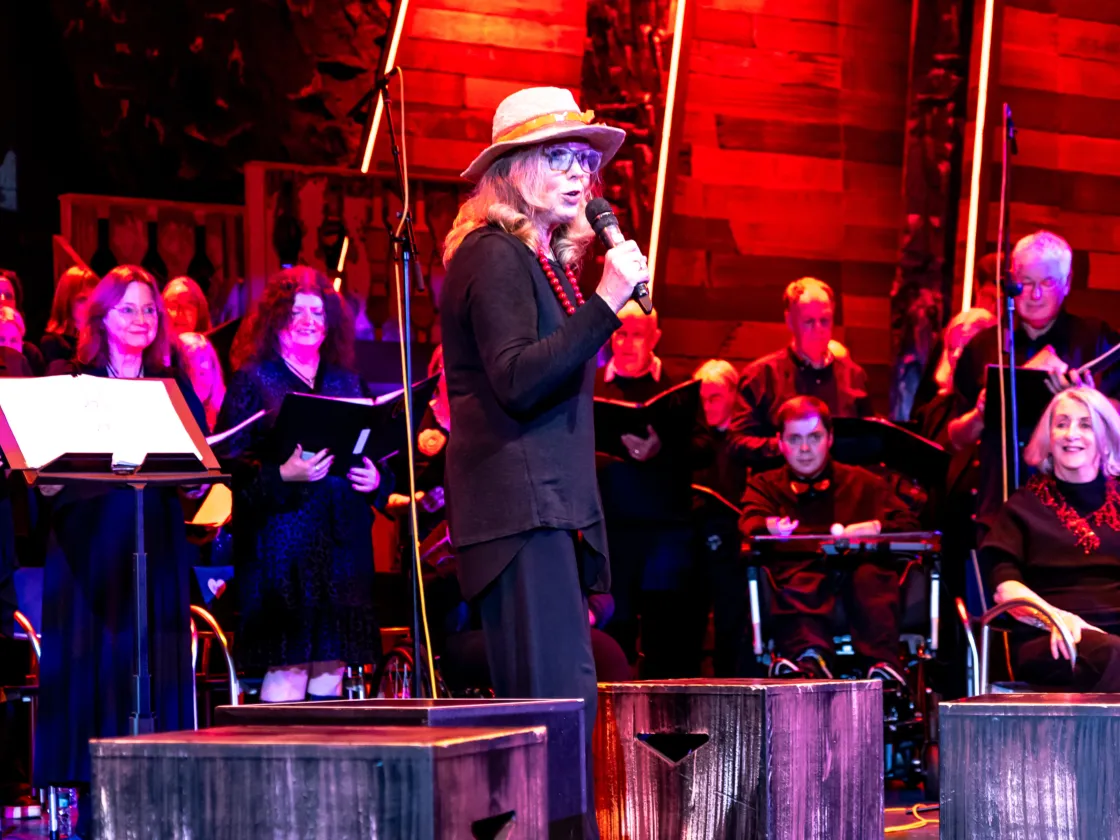 Lady on a microphone in front of a choir