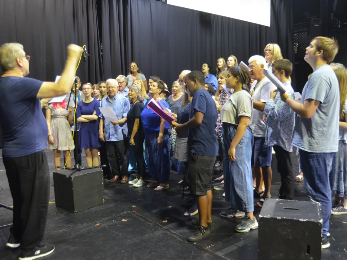 Group of people singing with a conductor in front