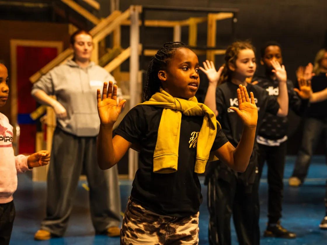 A group of children dancing and acting on stage.