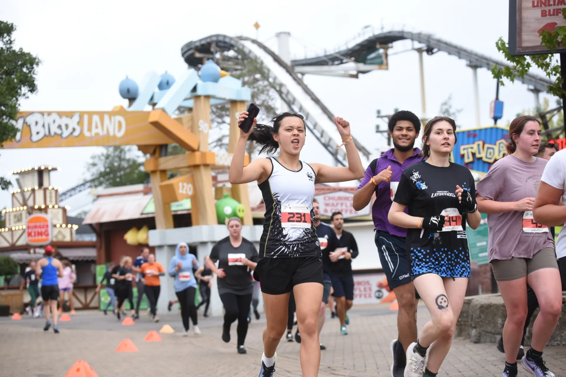 Runners with a rollercoaster behind them at Thorpe park