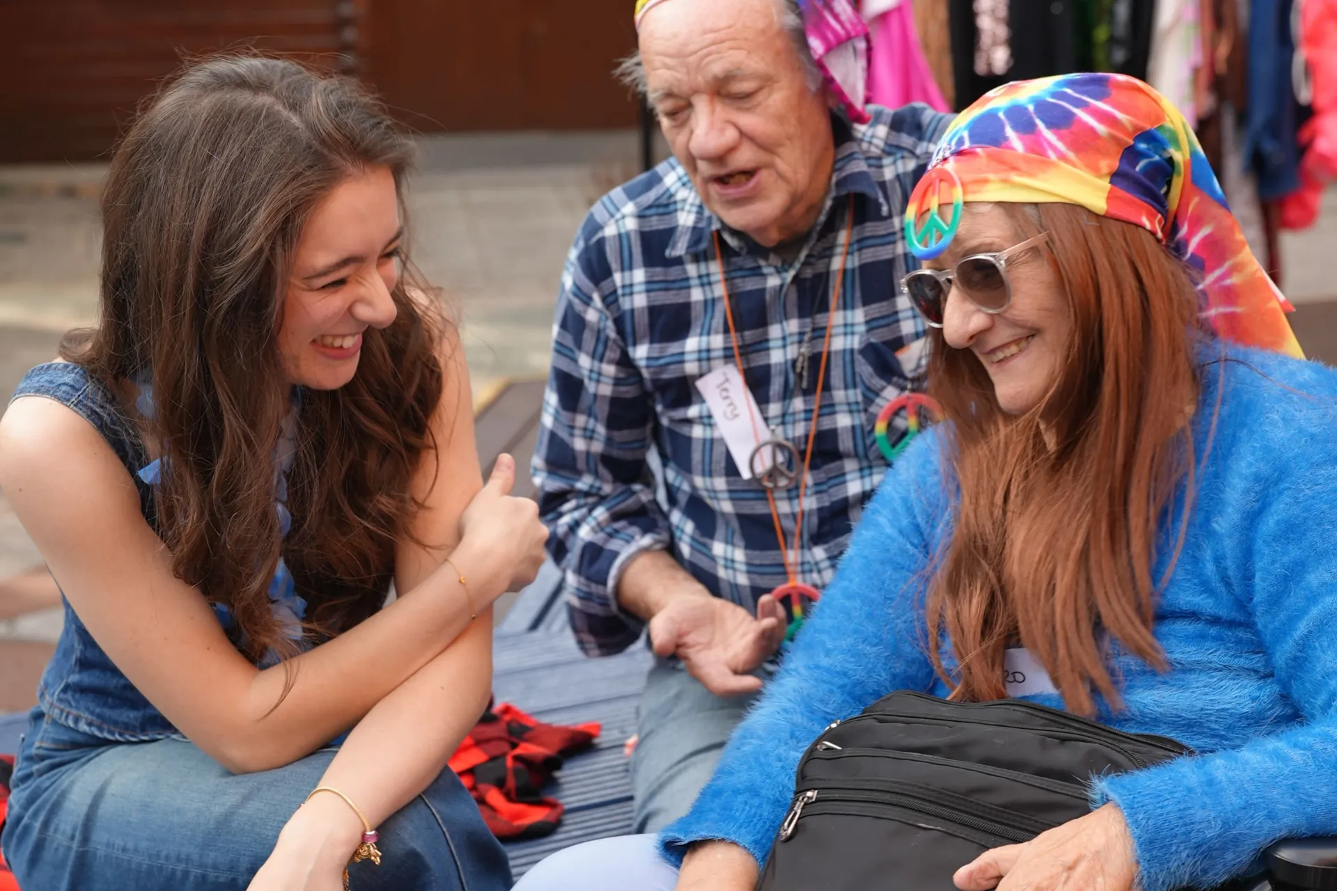 A young Chickenshed member sat outside with two Gladrags members, chatting and giggling together