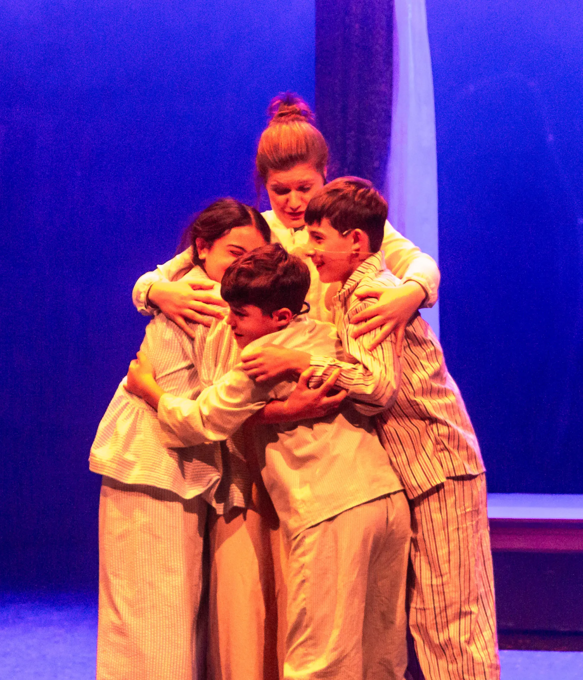 Group of children hug on stage in pyjamas